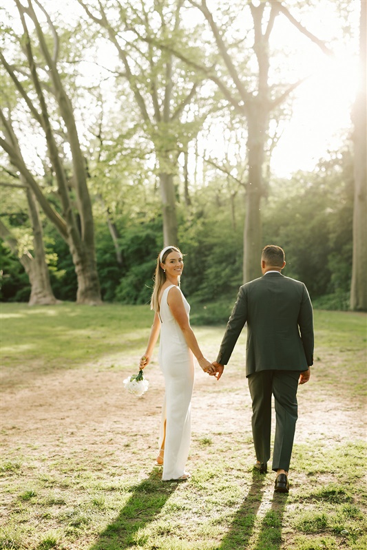 Bride and groom holding hands walking away from the camera with bride turning her head over her shoulder