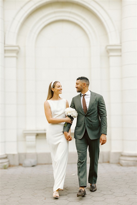 Bride and groom walking towards camera smiling at each other