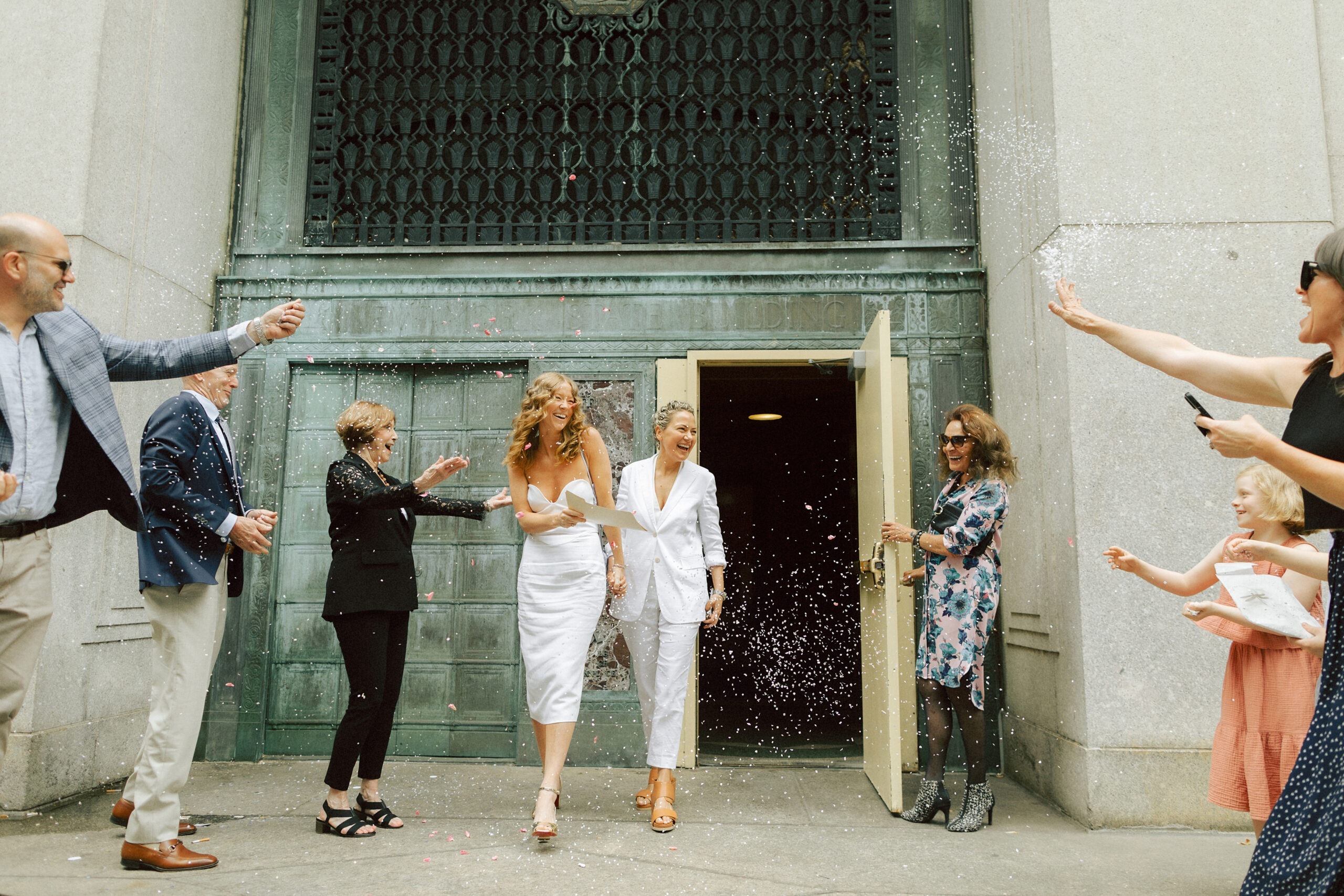 Catie and Jane's NYC City Hall exit after their New York City Hall elopement, surrounded by friends and family throwing confetti.