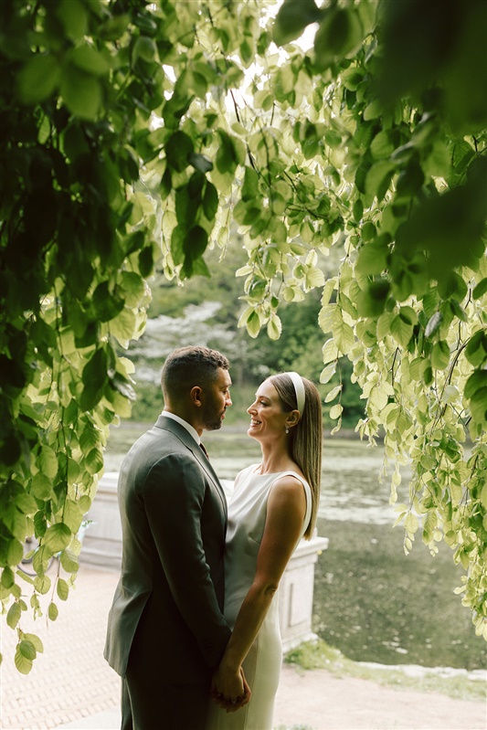 Bride and groom photos between leaves with them facing each other laughing