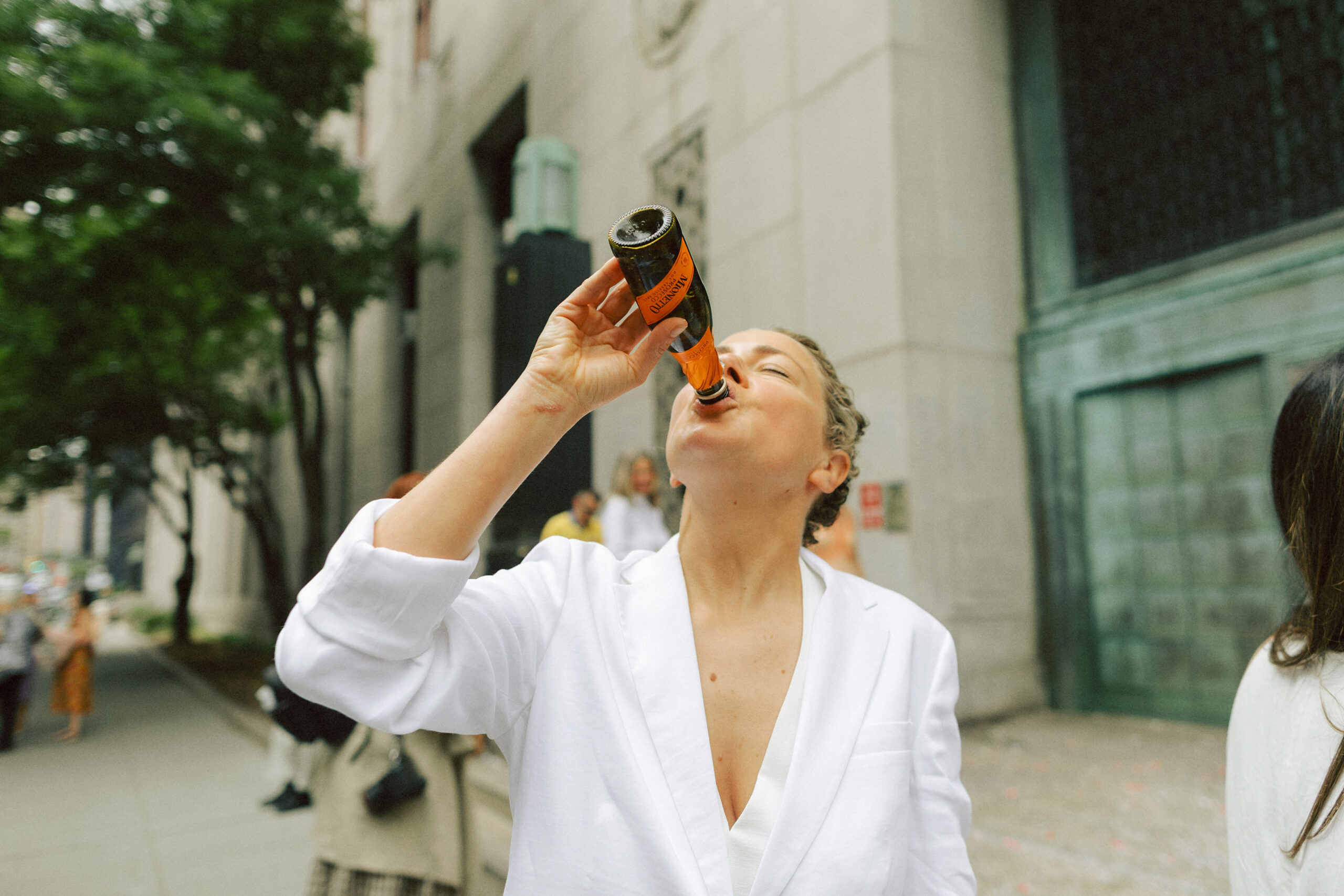 Bride celebrating her New York City Elopement, drinking champagne out of the bottle after exiting the city hall elopement.