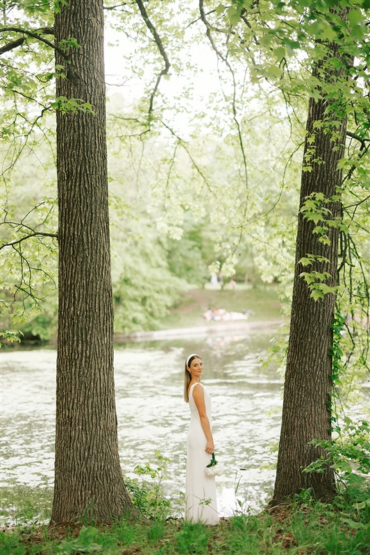 Bridal portrait of bride between trees and looking over shoulder