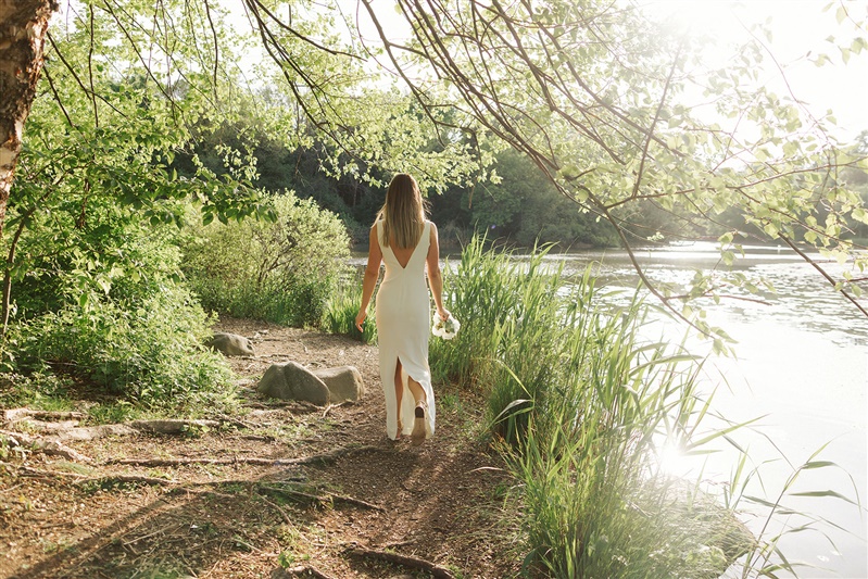 Photo of bride walking away from camera towards waterfront ceremony site at Brooklyn's Prospect Park