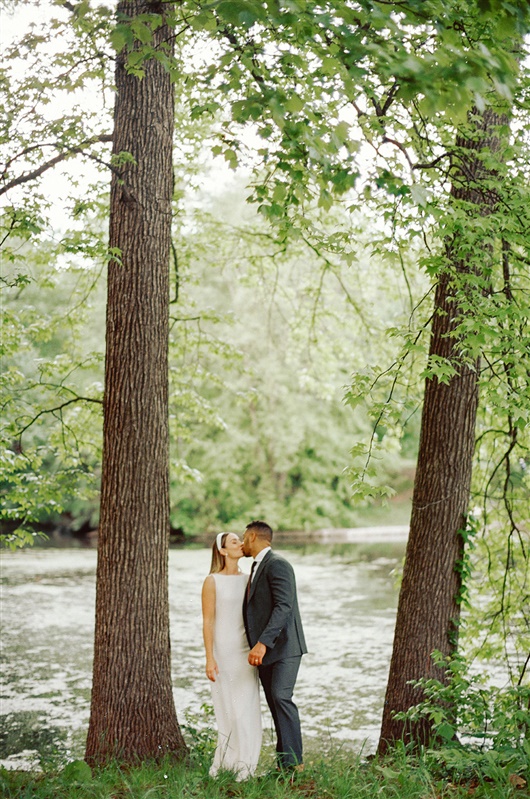 Bride and groom share a kiss in between trees at Prospect Park wedding