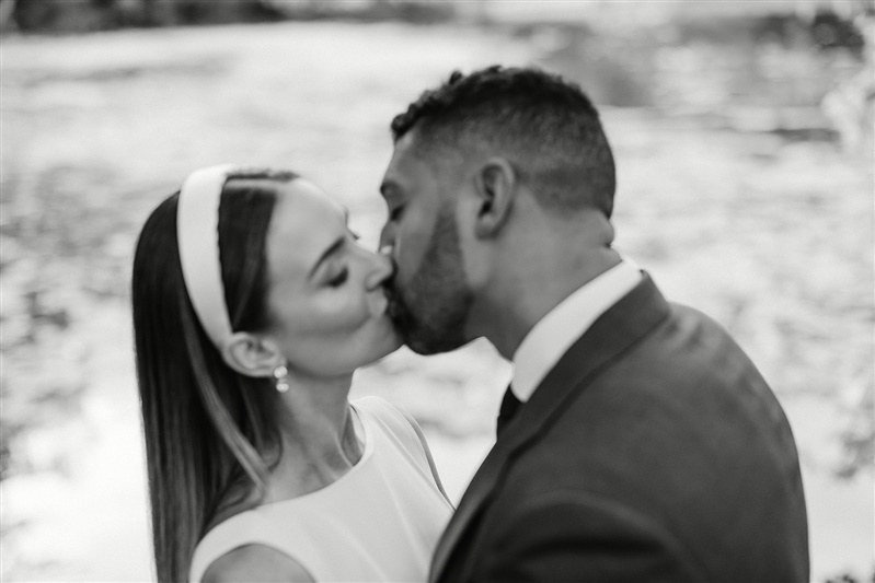 Black and white photo of bride and groom kissing