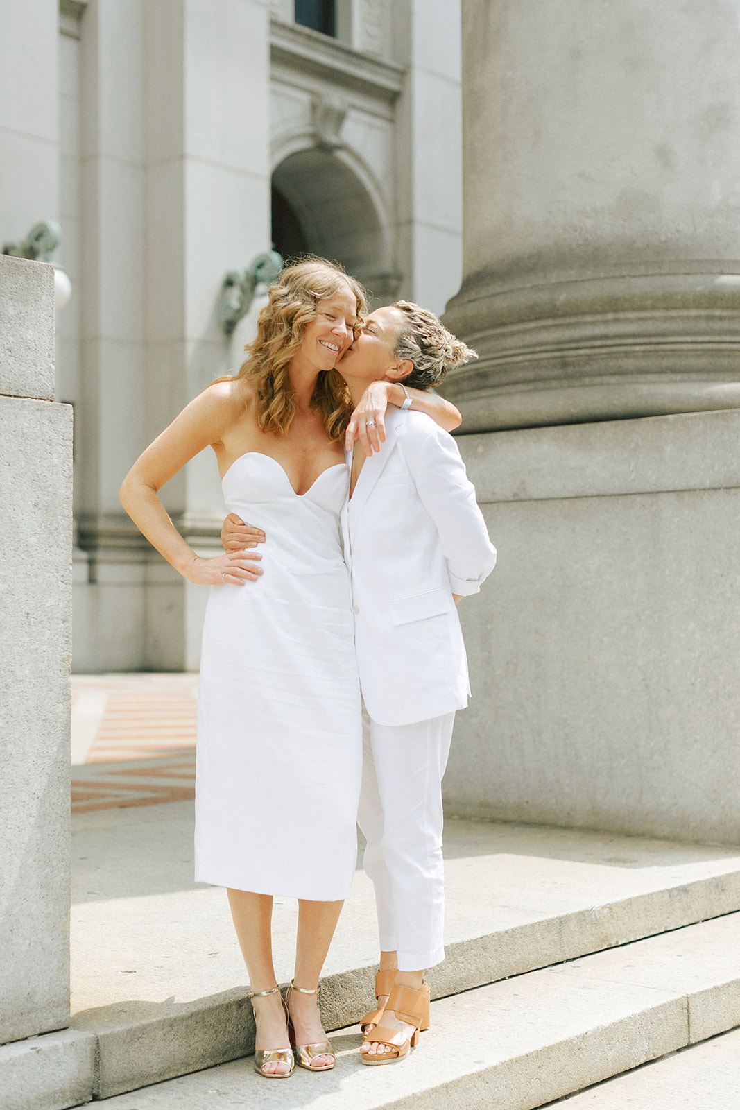 Bride kissing her wife on the cheek after leaving their NYC elopement at their city hall wedding.