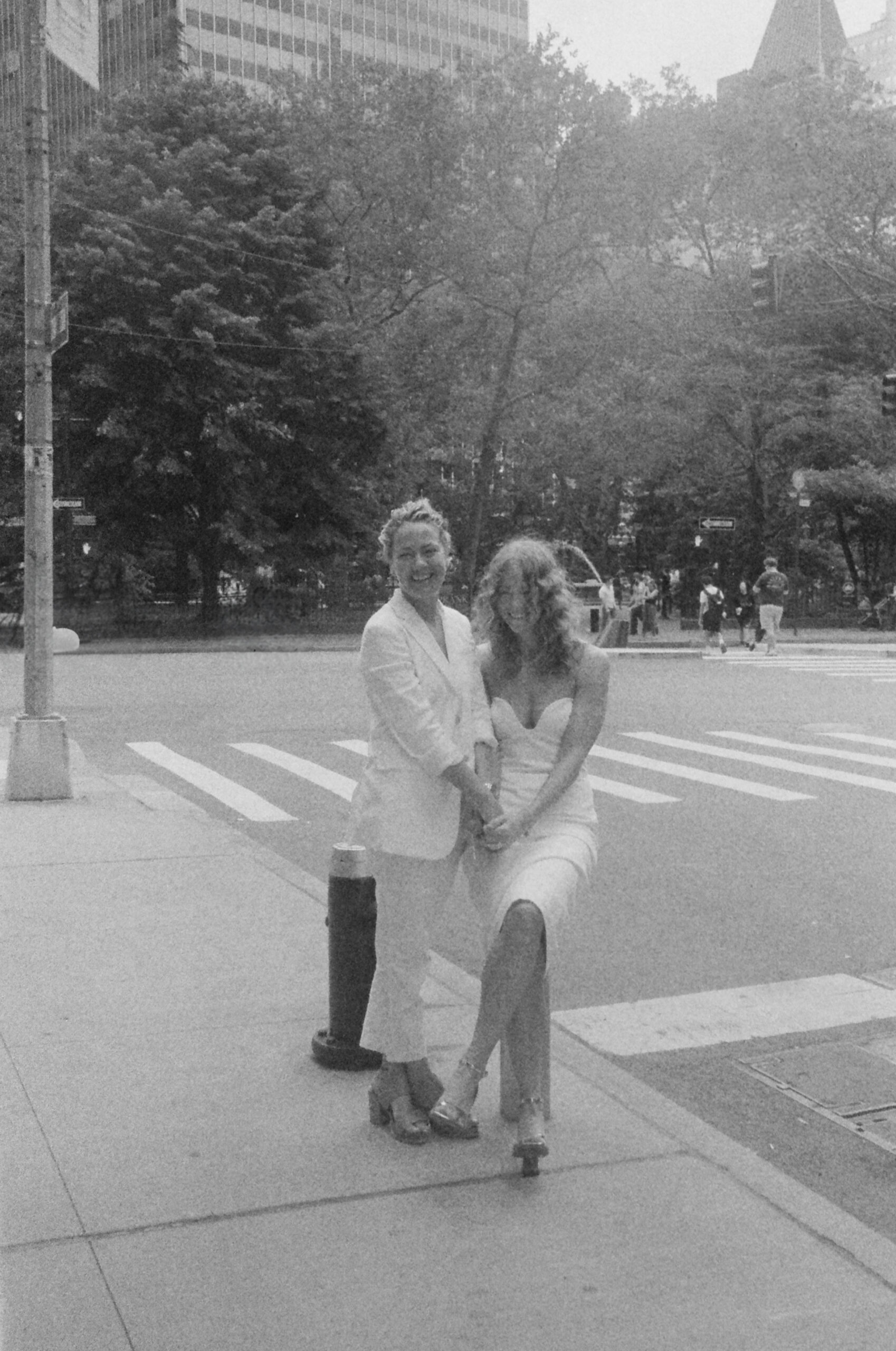 Film wedding photo of the brides after their elopement holding hands in front of New York City views