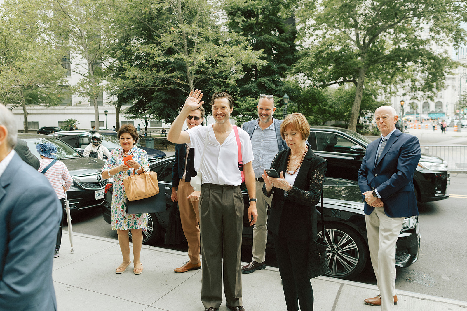 Man waving at the couple as they walk into the NYC city hall for their civil ceremony