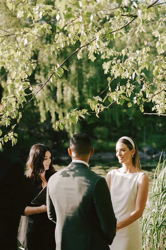 Bride smiling at groom during sunlit waterfront elopement ceremony in Brooklyn's Prospect Park