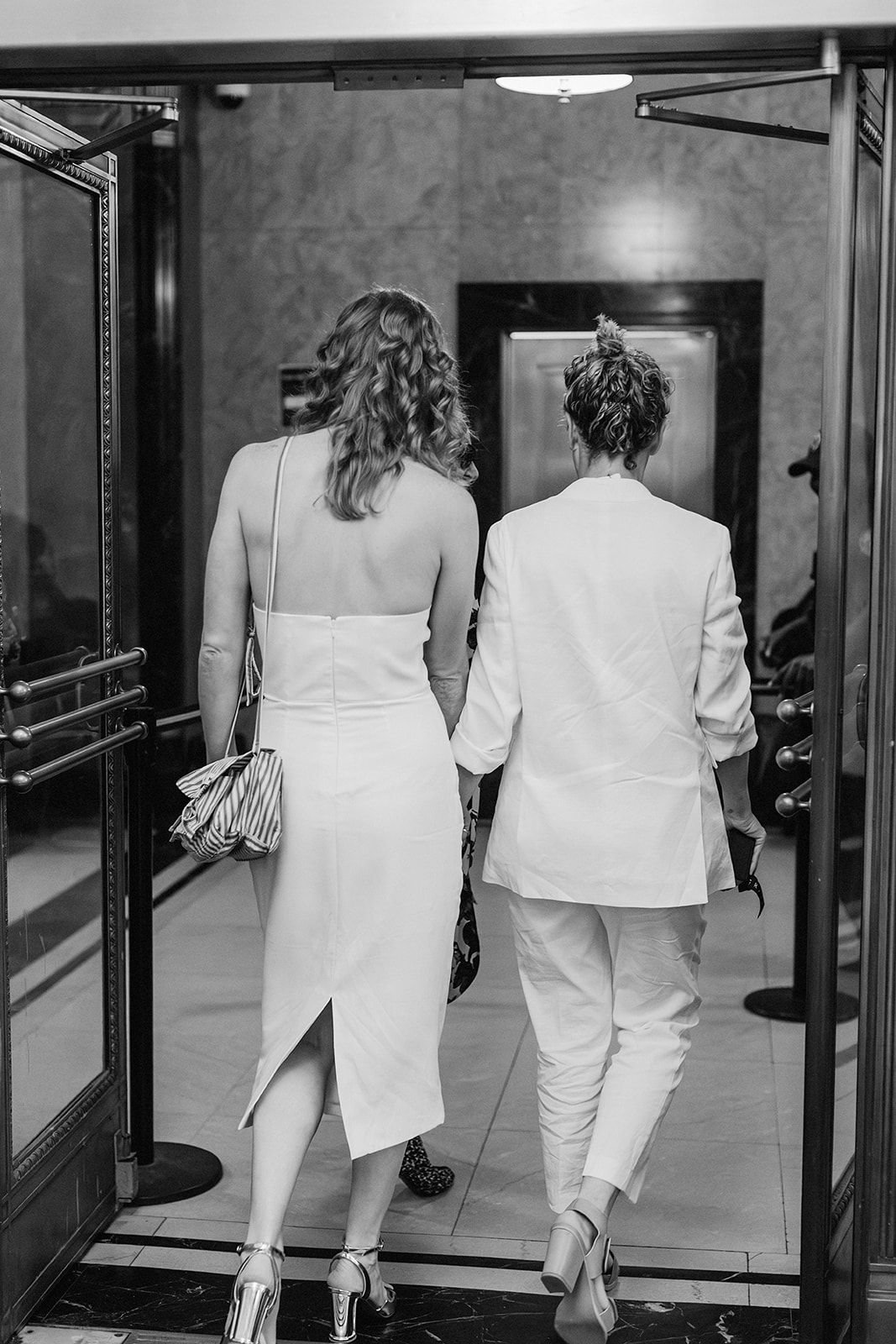 Catie and Jane leaving their New York same sex wedding that took place at the NYC city hall in all white civil ceremony outfits
