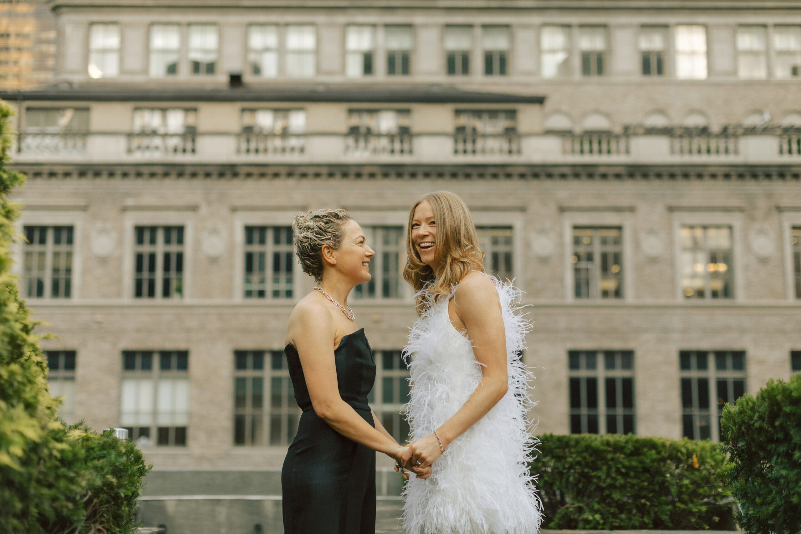 Couple at wedding reception holding hands and laughing in front of New York City backdrop