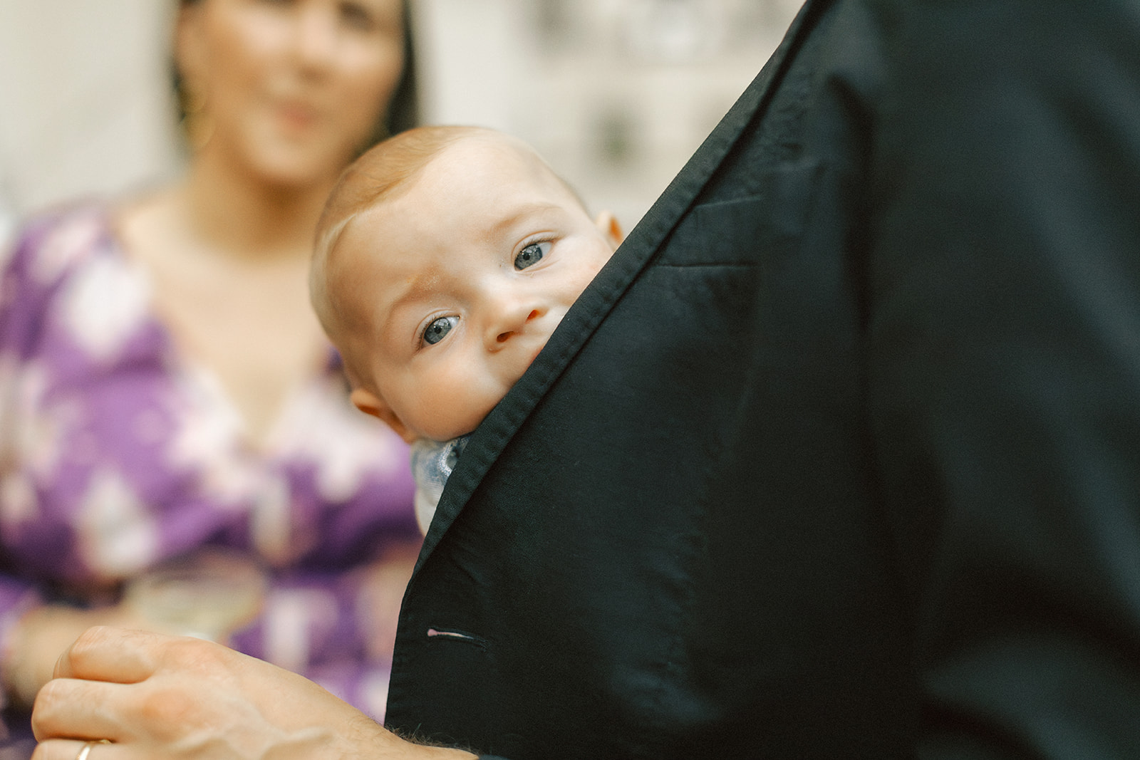 Photo of baby popping his head out from under a tuxedo at wedding