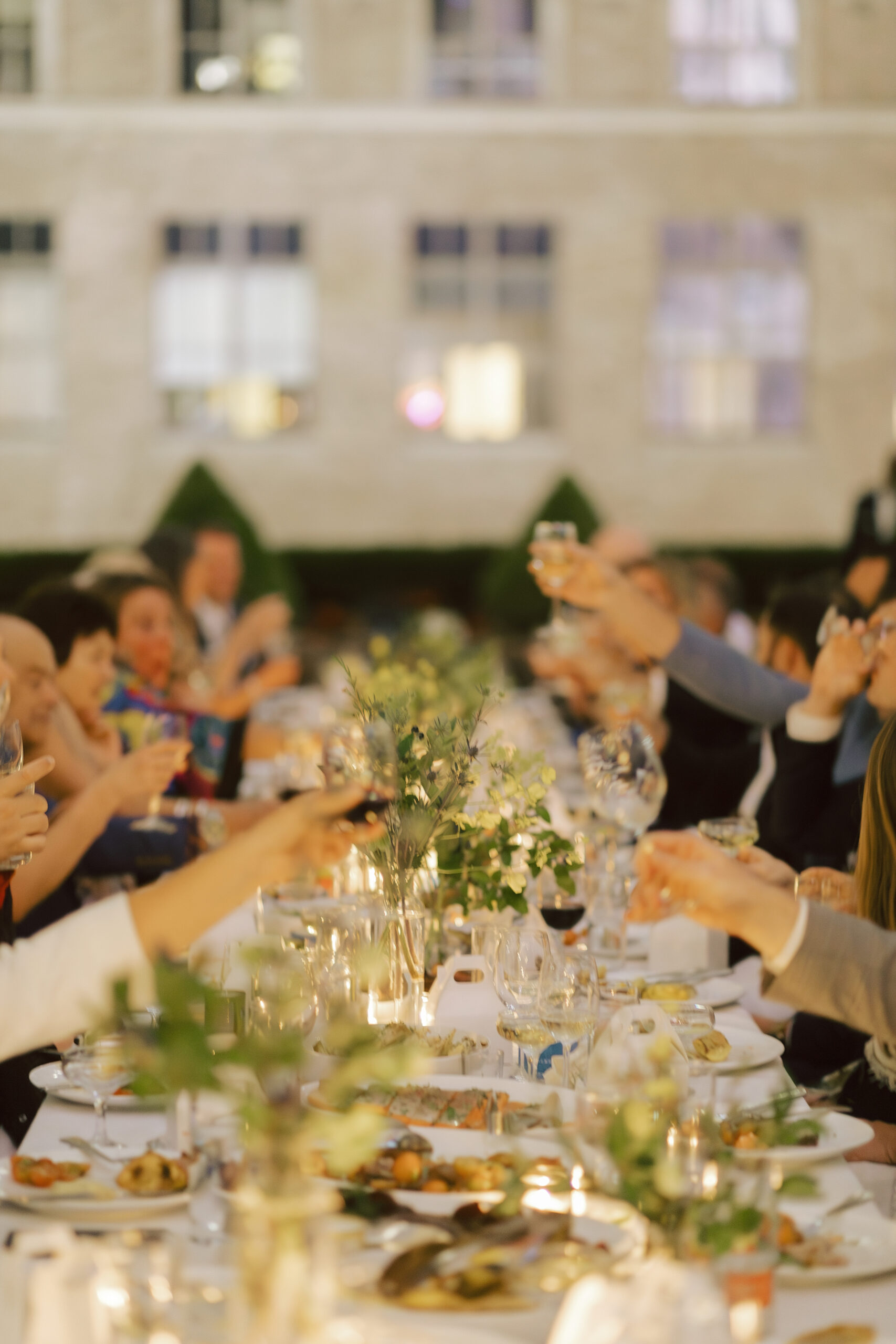 Photo from wedding reception with a candlelit dinner table and guests toasting their drinks