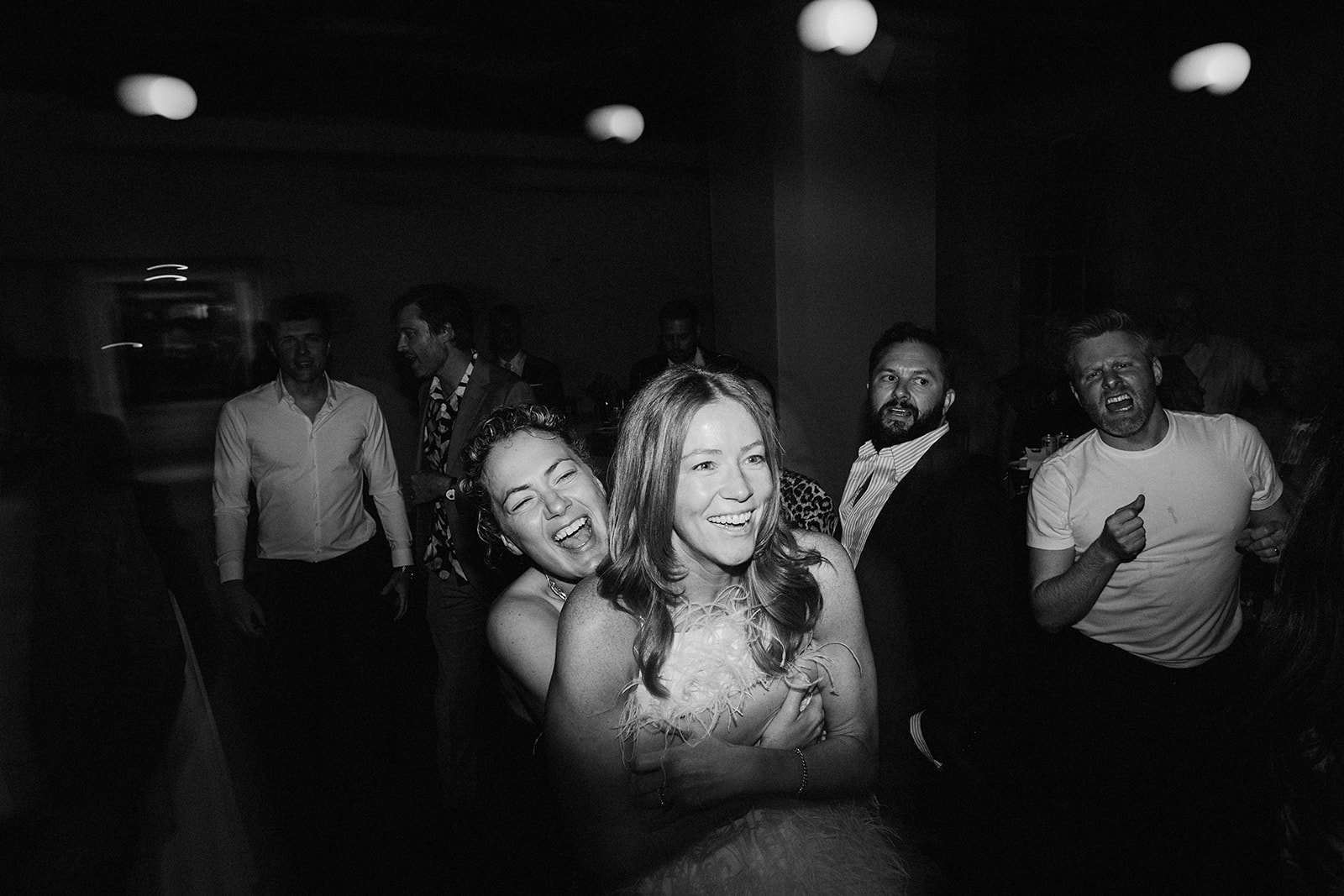 Wedding reception photos with one bride hugging the other bride from behind in the middle of a dance