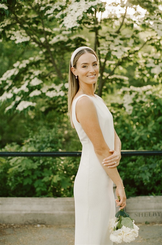 Bride posing for bridal portraits during Prospect Park wedding, wearing a high neck wedding dress and white headband