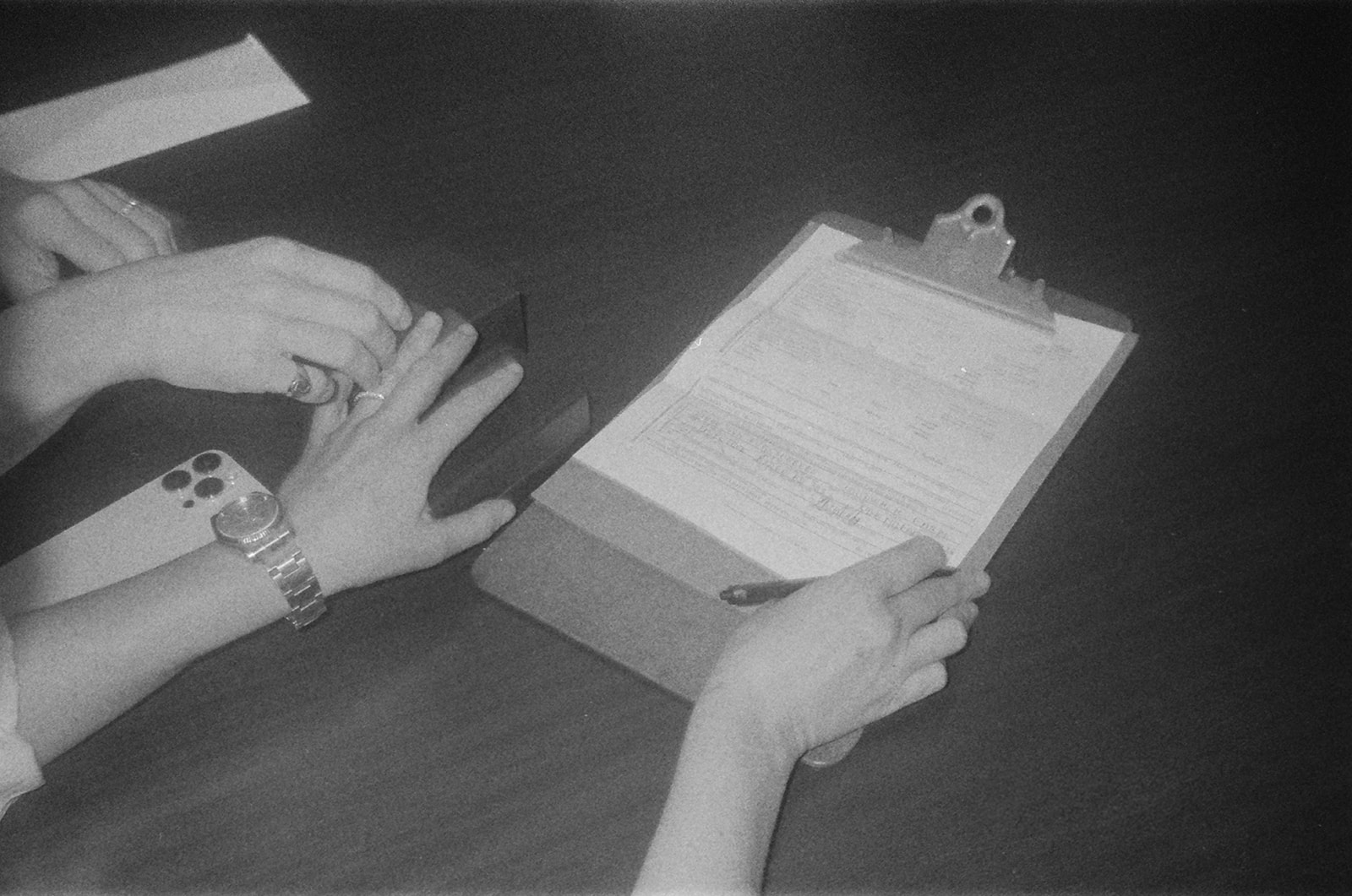 The couple gently holding pinkies as they sign their marriage license after their NYC elopement