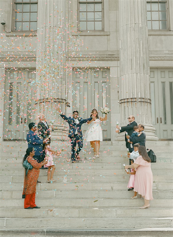 Couple celebrating their elopement with confetti on the steps of Brooklyn City Hall